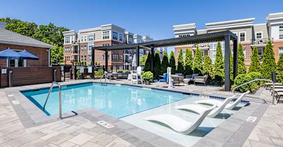 A swimming pool surrounded by a stone patio and lounge chairs.