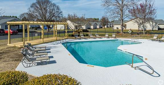 A swimming pool with a sun lounger and a fence.