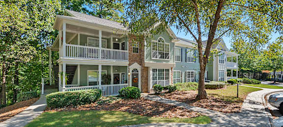 A large house with a white porch and a tree in front.