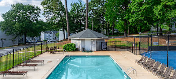 A swimming pool surrounded by a black fence and trees.