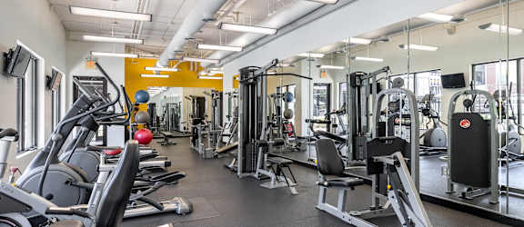 a gym with cardio equipment and weights on the floor