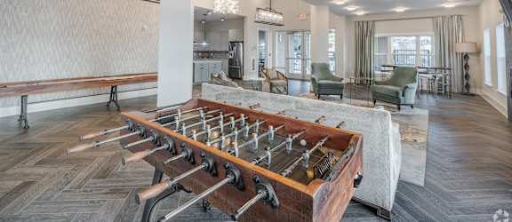 a communal area with a ping pong table in the center of the living room
