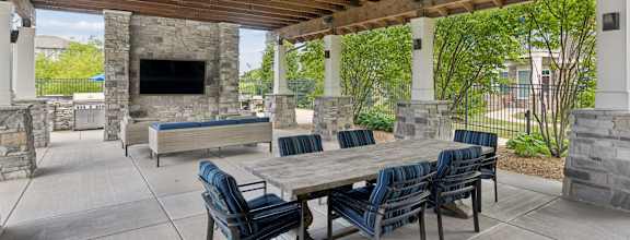 A patio with a table and chairs and a stone fireplace.