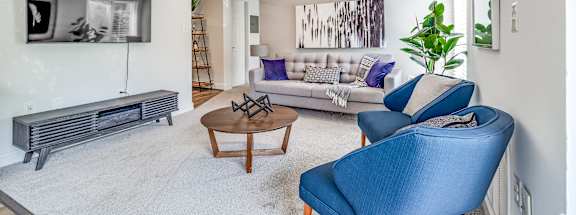 A living room with a blue chair and a grey sofa.