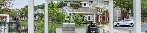 the outdoor kitchen is under a white roof with a grill at Carlton Park Apartment Homes, Mississippi, 39232