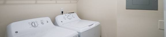 two washers and a dryer in a laundry room with a blue door at The Vineyard at Castlewoods Apartment Homes in Brandon, 39047
