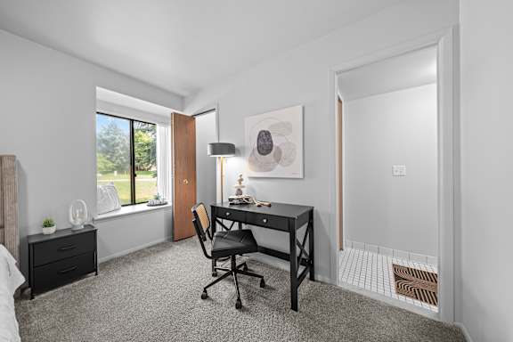 A room with a desk and a chair in it.