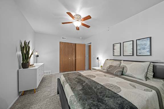 A bedroom with a bed, nightstands, and a ceiling fan.