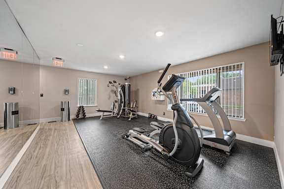 A gym with a treadmill, elliptical machines and other exercise equipment.