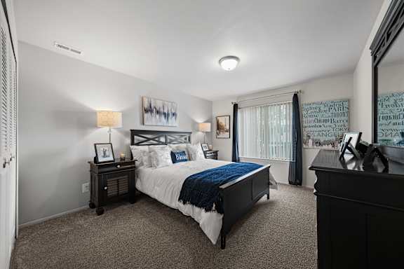 A bedroom with a bed, nightstand, and a painting on the wall.