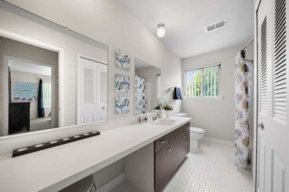 A white bathroom with a large mirror and a white sink.