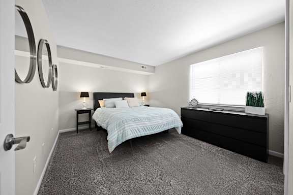 A bedroom with a bed, nightstand, and window.