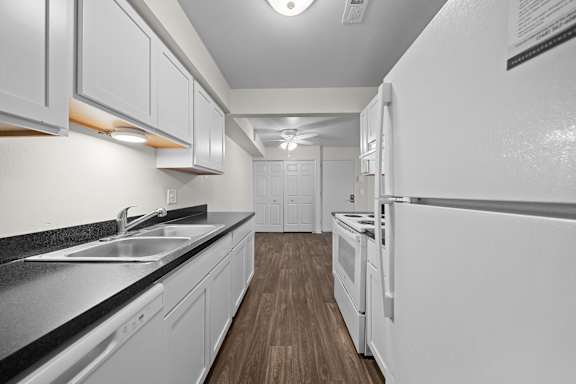 A kitchen with white cabinets and a black countertop.
