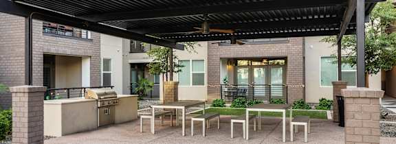 A swimming pool area with sun loungers and a blue umbrella in front of apartment buildings.
