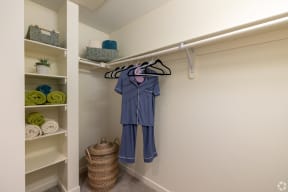 a large walk in closet with pajamas hanging up and 
shelves