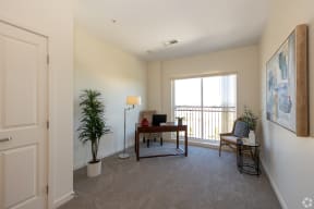 an office or second bedroom with desk chair and large window
