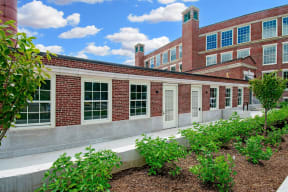 the front of a brick building with windows and a garden at Beverly Village for Living & the Arts Apartments, Massachusetts, 01915