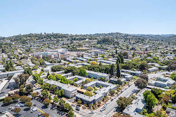 A bird's eye view of a residential area with houses, trees, and roads.