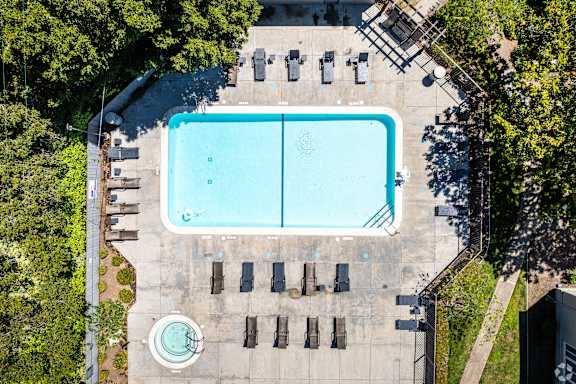 An aerial view of a swimming pool surrounded by trees and chairs.