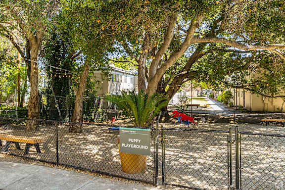 A sign that says Puppy Playground is on a fence.