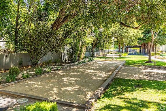 A park with a pathway, trees, and a bench.