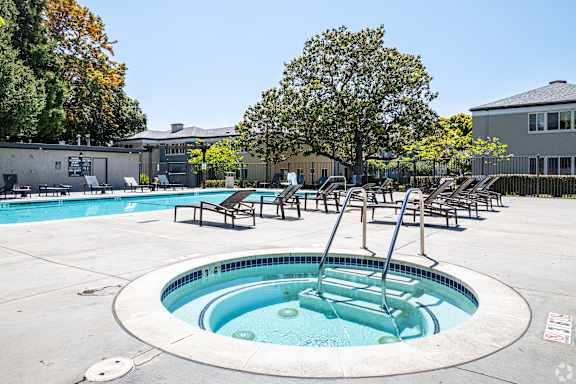 A hot tub sits in the middle of a pool surrounded by chairs.