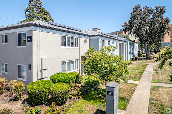 A residential building with a grey facade and a green lawn in front.