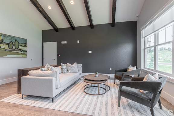 A living room with a white couch, a wooden coffee table, and a large painting on the wall.