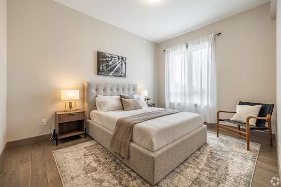 A bedroom with a large bed, a chair, and a painting on the wall.