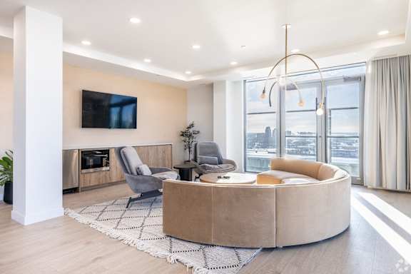 A modern living room with a large window and a flat screen TV mounted on the wall.