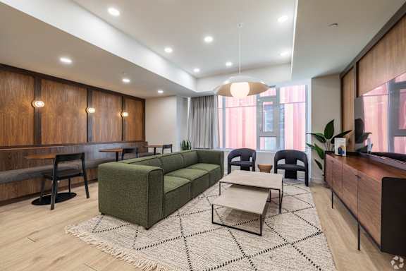 A modern living room with a green sofa and a patterned rug.