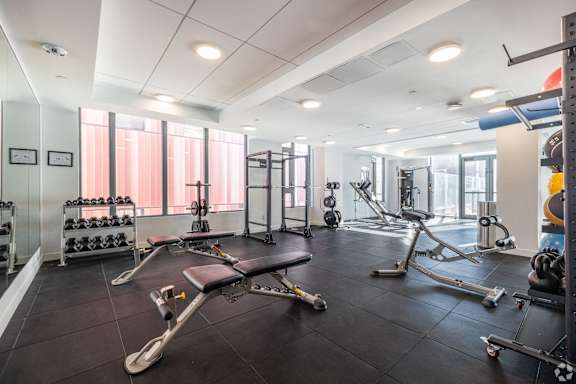 A gym with a variety of equipment including weights and a leg press machine.