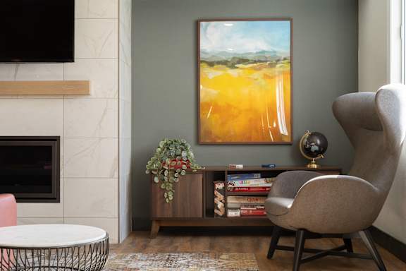 A living room with a fireplace, a painting, a chair, and a globe.