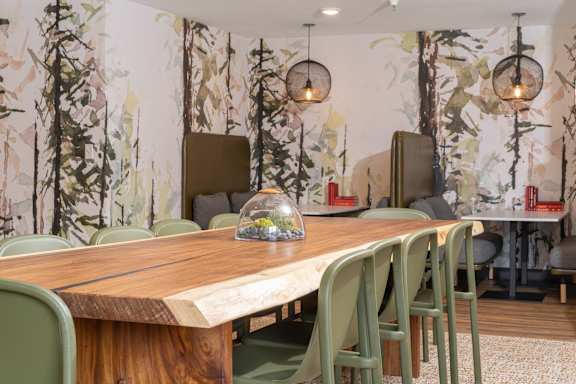 A dining table with green chairs and a vase on top of it.