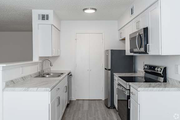 A kitchen with white cabinets and black appliances.