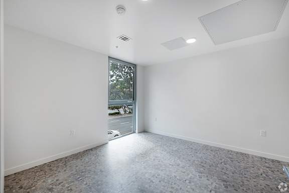 A large empty room with a doorway leading to a balcony.