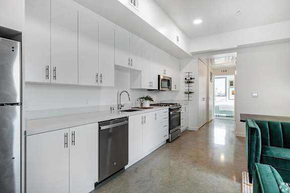 A modern kitchen with white cabinets and a green couch.