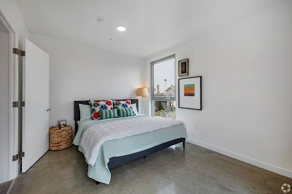 A bedroom with a bed, pillows, and pictures on the wall.