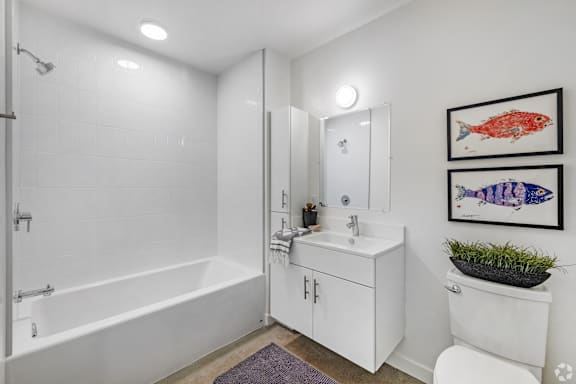 A white bathroom with a white tub, sink, and toilet.