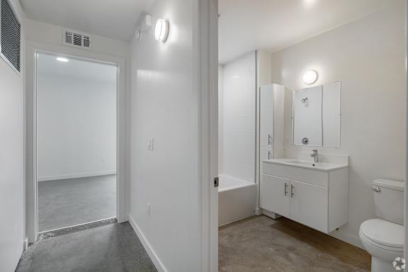 A white bathroom with a toilet, sink, and mirror.
