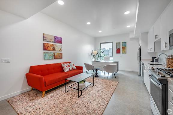 A red couch sits in a living room with a glass table and chairs.