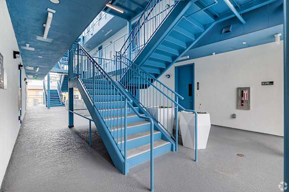 A blue staircase in a building with a white wall and a fire extinguisher.