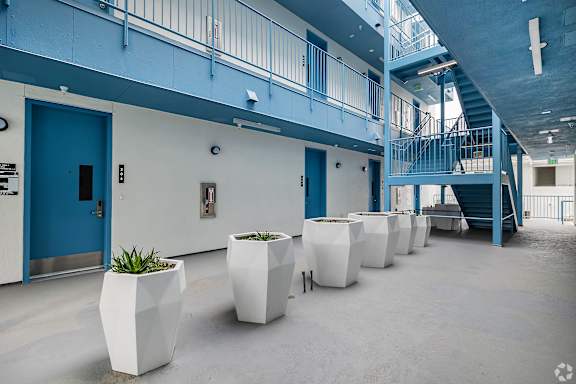 A hallway with blue doors and white planters.