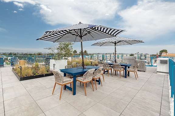 A patio with a table and chairs under umbrellas.