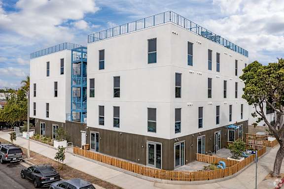 A white building with a blue balcony on the top floor.