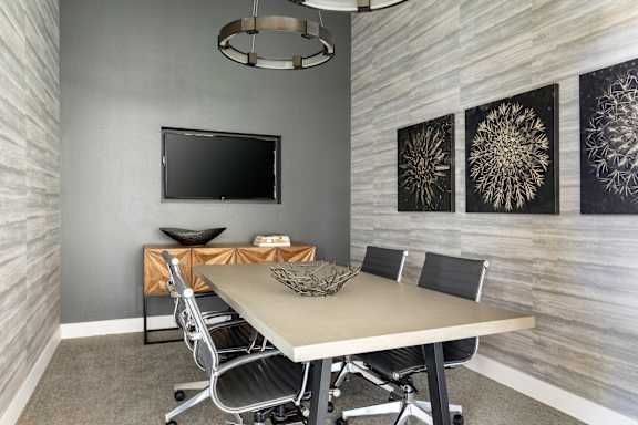 A conference room with a table, chairs, and a television.