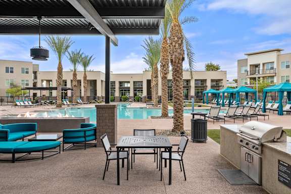 A patio with a table and chairs overlooking a pool.