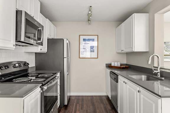A kitchen with a stove, microwave, refrigerator, and cabinets.