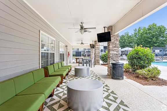 A long green sofa is on the left side of a white table.