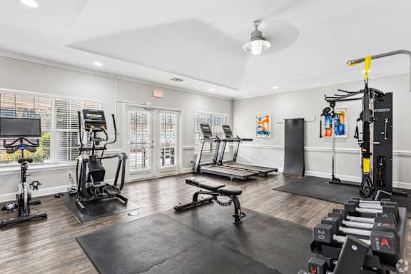 A spacious home gym with a variety of equipment including a treadmill, stationary bike, and weight rack.